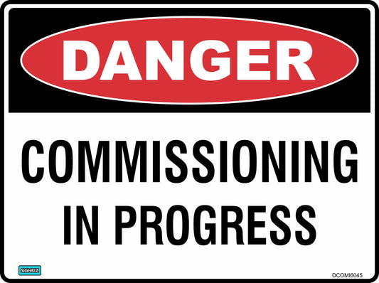 The Danger Commissioning In Progress sign is a rectangular safety notice featuring a red "DANGER" oval at the top and bold black "COMMISSIONING IN PROGRESS" text on a white background, providing clear hazard warning.
