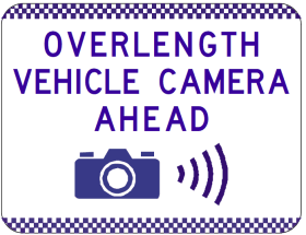 The G6-345-2n sign features a rectangular design with a checkered border and the message "OVERLENGTH VEHICLE CAMERA AHEAD" in purple. Below the text is a camera icon with sound wave lines, emphasizing a symbolic camera warning.