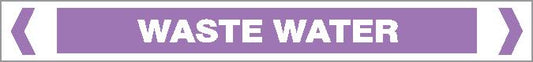 A rectangular purple sign reading "ACID / ALKALI - WASTE WATER" in white text, centered and bordered by white and gray lines with angled brackets at each end.