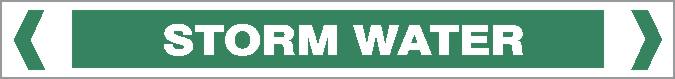 A green rectangular Pipe Marker labeled "STORM WATER" in bold white capital letters, bordered by white inward-pointing arrows on each end.