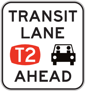 The R7-220n Transit Lane T2 Ahead sign features "TRANSIT LANE AHEAD," a red oval with "T2," and a black car icon with two people, designed to Australian Standards.