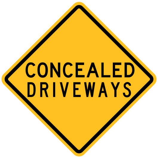 The W5-55-2n - Concealed Driveways sign is a yellow, diamond-shaped road sign with a black border that features the words "CONCEALED DRIVEWAYS" in large, black uppercase letters.