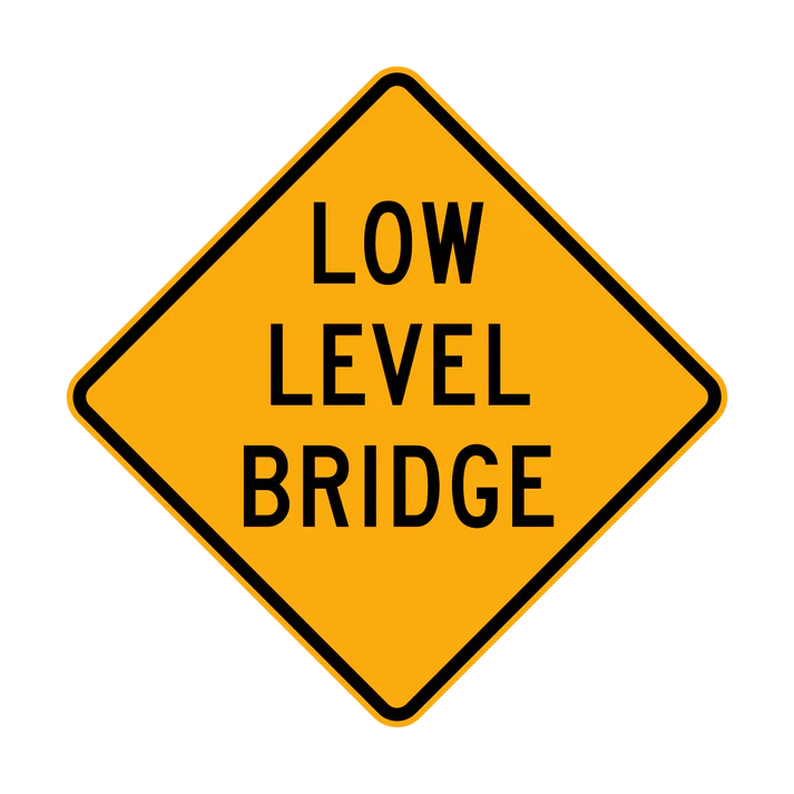 A W5-8 "Low Level Bridge" sign features a yellow diamond shape with "LOW LEVEL BRIDGE" in black capital letters centered on the face.