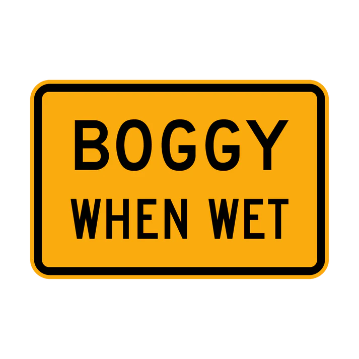 The W8-21 - Boggy When Wet sign is a rectangular yellow road sign with a black border and the words "BOGGY WHEN WET" in bold, black capital letters.